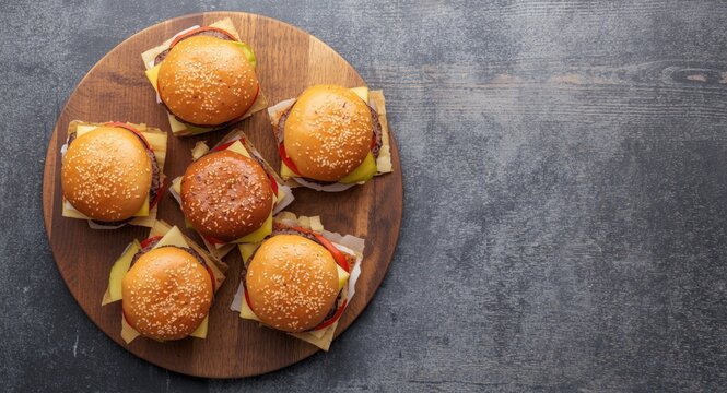 Varied mini burgers served on a wooden plank including copy space for text placement