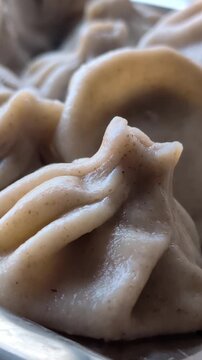 Delicious steamed momo dumplings, a traditional tibetan and nepalese dish with pleated dough, served hot in a metal steamer for an authentic asian culinary experience