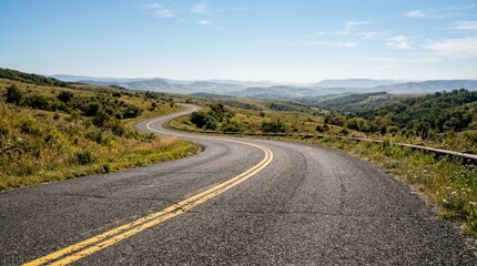 Obraz premium Winding Mountain Road with Yellow Lines, Scenic Landscape, Blue Sky