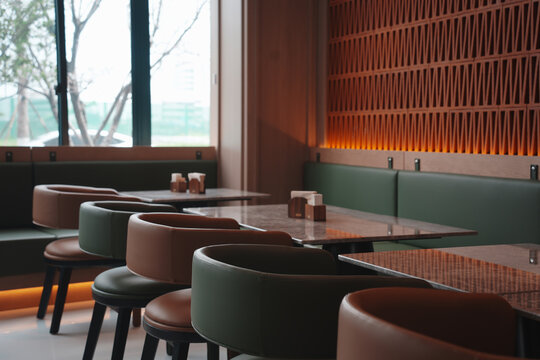 Modern caf&eacute; interior with green and brown color scheme featuring booth seating and wooden lattice wall lighting