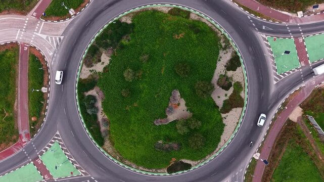 Aerial of a multi-lane roundabout with central green island, marked entries, splitter islands, cycle lanes and traffic signage showing efficient urban traffic flow design