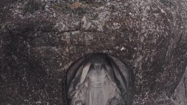 Nossa Senhora da Boa Estrela statue carved in granite niche within Serra da Estrela Portugal showing religious sculpture embedded in rock face with weathered texture and sacred symbolism, descent