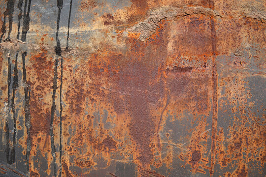 Close-up texture of weathered, rusty metal with dark streaks and pitting