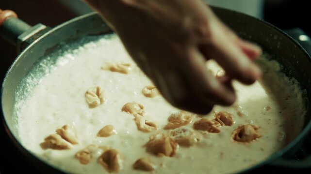 Italian Tortellini Cooking In Creamy White Sauce Inside Frying Pan. Meal Preparation In Skillet
