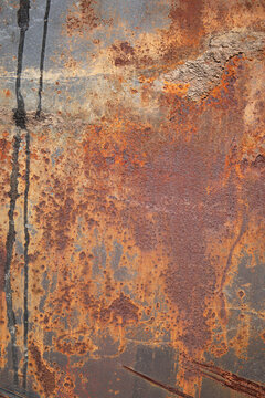 Close-up texture of weathered, rusty metal with dark streaks and pitting