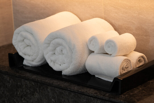 Set of Rolled White Cotton Towels on Black Tray in Luxury Bathroom