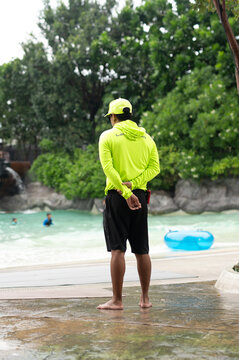 Professional Lifeguard in Neon Uniform Watching Over Tropical Wave Pool