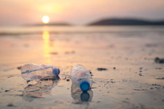 Environmental Pollution Concept with Plastic Waste on Coastline During Sunrise