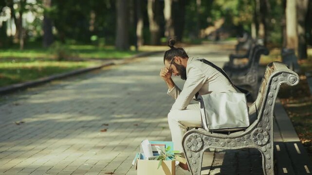Depressed Businessman Sitting On Bench After Job Loss. Sad Employee Reflecting On Professional Failure. Depression After Being Fired
