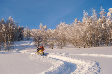 Athlete on a snowmobile moving in the winter forest in the mountains of the Southern Urals