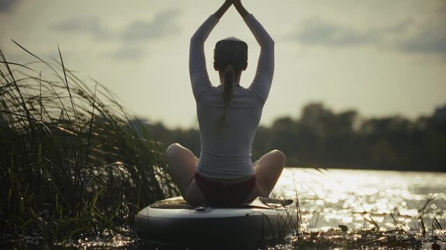 Practicing Yoga On Sup Board. Woman Meditating In Lotus Pose