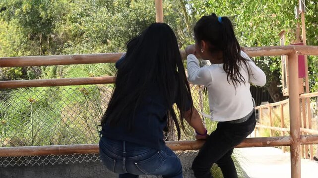 GIRLS CLIMBING A ROCK IN THE PARK.