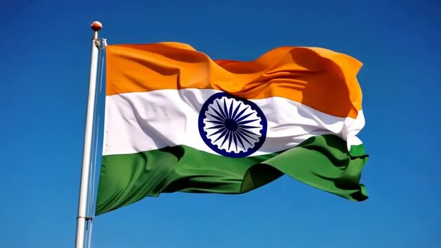 Indian national flag waving in the wind against a clear blue sky. It features saffron, white, and green horizontal stripes with the navy blue Ashoka Chakra in the center.