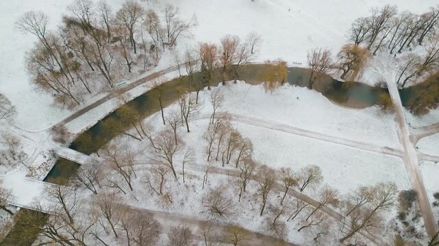 Drone to reveal the
Monopteros in Munich&rsquo;s English Garden, surrounded by snow on a sunny winter morning with serene park atmosphere.