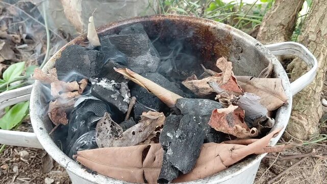 Burning Charcoal Briquettes and Dry Leaves for Traditional Fish Grill