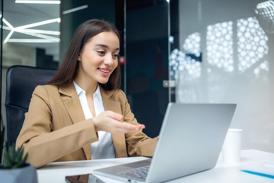 Successful female manager in business suit using portable laptop to have online meeting videocall and talking with partners. beautiful caucasian woman working in modern office.