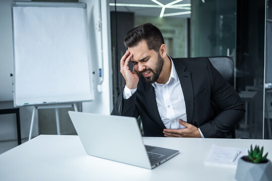 businessman in shirt holds hand on stomach grimaced in pain.