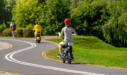 Obraz premium Girl rides an electric scooter in the summer Park