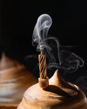 close up of a candle smoking in a lemon meringue birthday cake