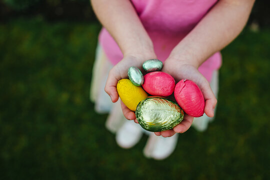 Easter chocolate eggs in child's hands, top view