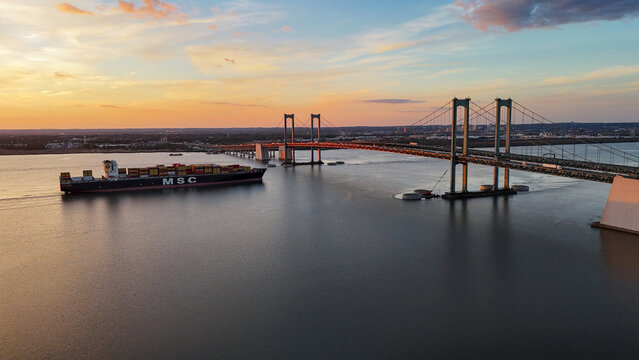 MSC container ship passing under Delaware Memorial Bridge at sunset