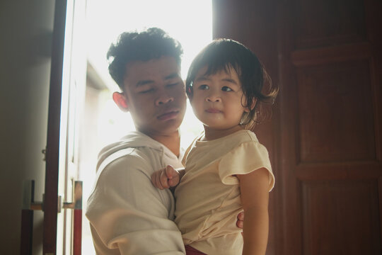 Caring young man carrying baby sister back into the house through the door. Silhouette family moment of protection and homecoming