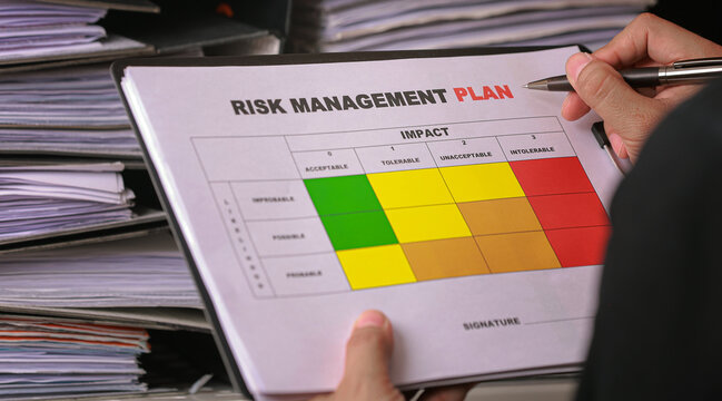 Focused manager holding risk management plan business document with matrix strategy using pen over paper stack for serious evaluation