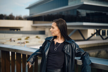Obraz premium Woman standing near modern building with water view on sunny day in urban area