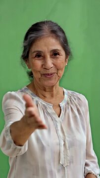 Latina elderly woman on green screen waves hello and then beckons warmly with welcoming charm for family invitation hospitality greeting or service communication scenes latina woman