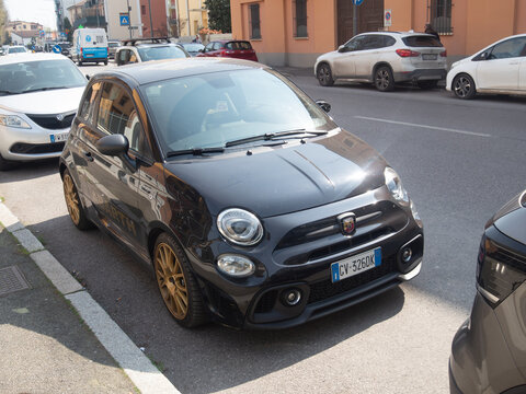 Abarth 595 Scorpioneoro parked on a city street in Italy, showcasing its sleek black design and gold wheels