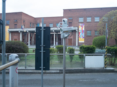 Logiplate ANPR camera monitoring urban street traffic with brick building, flags and columns in daytime city setting