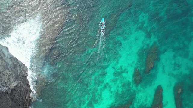 From abobe the S&atilde;o Tom&eacute; turquoise waters with a wooden boat leaving the beach below. The drone captures crystal-clear seas, and the serene beauty of this tropical island paradise.Africa