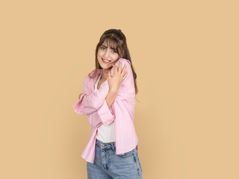 Happy caucasian woman hugging herself with warm smile, expressing comfort and self love, taking selfie mood, wearing pink shirt and denim, isolated on beige studio background with copy space.