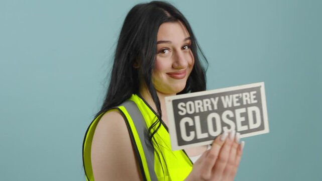 Female worker in safety vest showing a Sorry we are closed sign