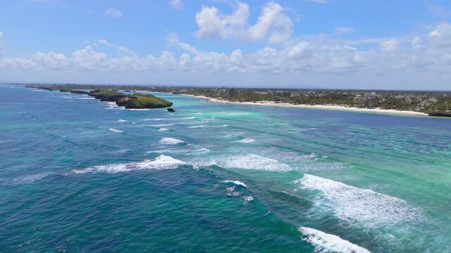 Aerial view of turquoise Indian Ocean waves breaking over coral reefs along the coastline and white sand shores at Watamu Beach, Kenya.