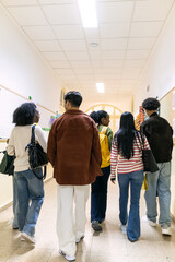 Group of diverse college students walking and communicating in a brightly lit school corridor, representing education and community © Koldo_Studio