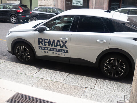 White corporate car with RE/MAX branding parked on a city street
