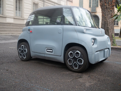 Citroen Ami electric microcar parked on an asphalt surface in front of a building