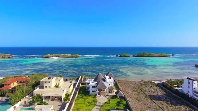 Aerial view of luxury villas and residential buildings overlooking turquoise water, coral reefs, and small islands at Watamu Beach, Kenya.