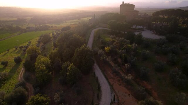 Breathtaking Tuscany Sunset. Val d'Orcia aerial 4K. Misty cypress road winding to luxury farmhouse. Golden light over rolling hills and traditional Italian villa landscape. 
