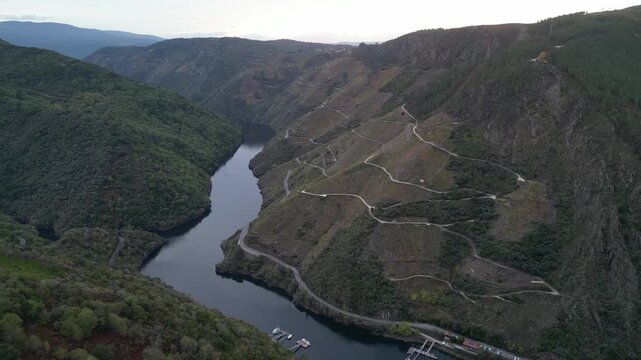 Aerial view of the River Sil Canyon winds between verdant hills, displaying a striking contrast of deep blues and greens, Ribeira Sacra, Lugo, Spain.