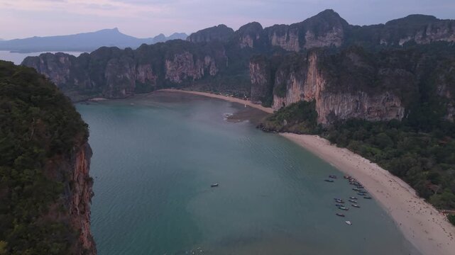 Aerial view of towering limestone cliffs meet the serene beach, creating a stunning contrast of textures and tones, Ao Nang, Krabi, Thailand.