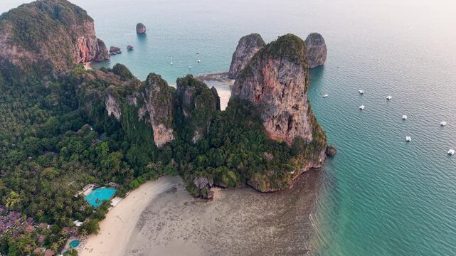 Aerial view of Railay Beach, where towering limestone cliffs meet the turquoise waters, interspersed with boats, Ao Nang, Krabi, Thailand.