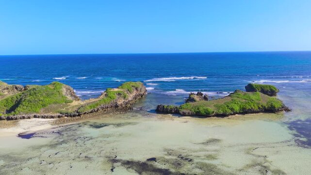 Aerial view of rocky islands and coral reefs along the coastline with small boats anchored in shallow turquoise water at Watamu Beach, Kenya.