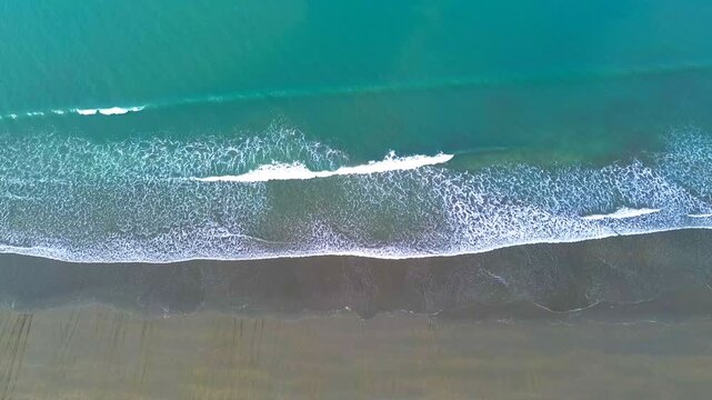 Aerial view of the rhythmic turquoise waves meeting the sandy shore, creating a mesmerizing contrast of textures and tones, Cox's Bazar, Chittagong Division, Bangladesh.