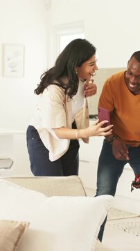 Vertical video: Pointing to child, couple angling purple phone for selfie in bright home, keys held