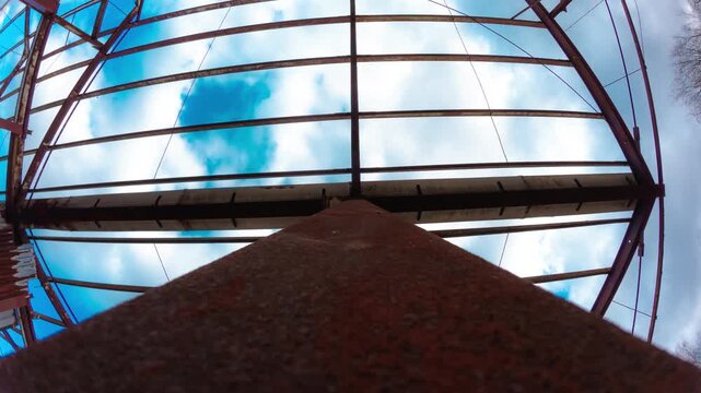 Abstract geometry of metal roof grid against blue sky and clouds time lapse. Minimal industrial lines perspective symmetry and sky movement composition timelapse. Modern design pattern structure