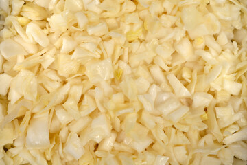 Fototapeta premium A detailed full frame background texture showing a pile of freshly chopped raw white cabbage pieces ready for cooking or salad