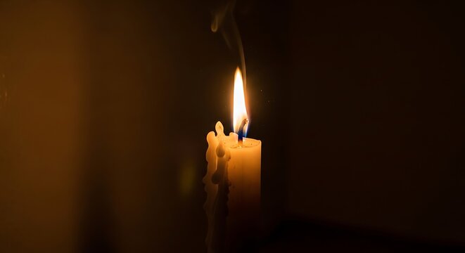 Burning candle with smoke in dark room