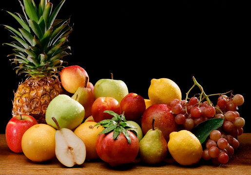 still life of mixed fruit photographed on wood with a black background